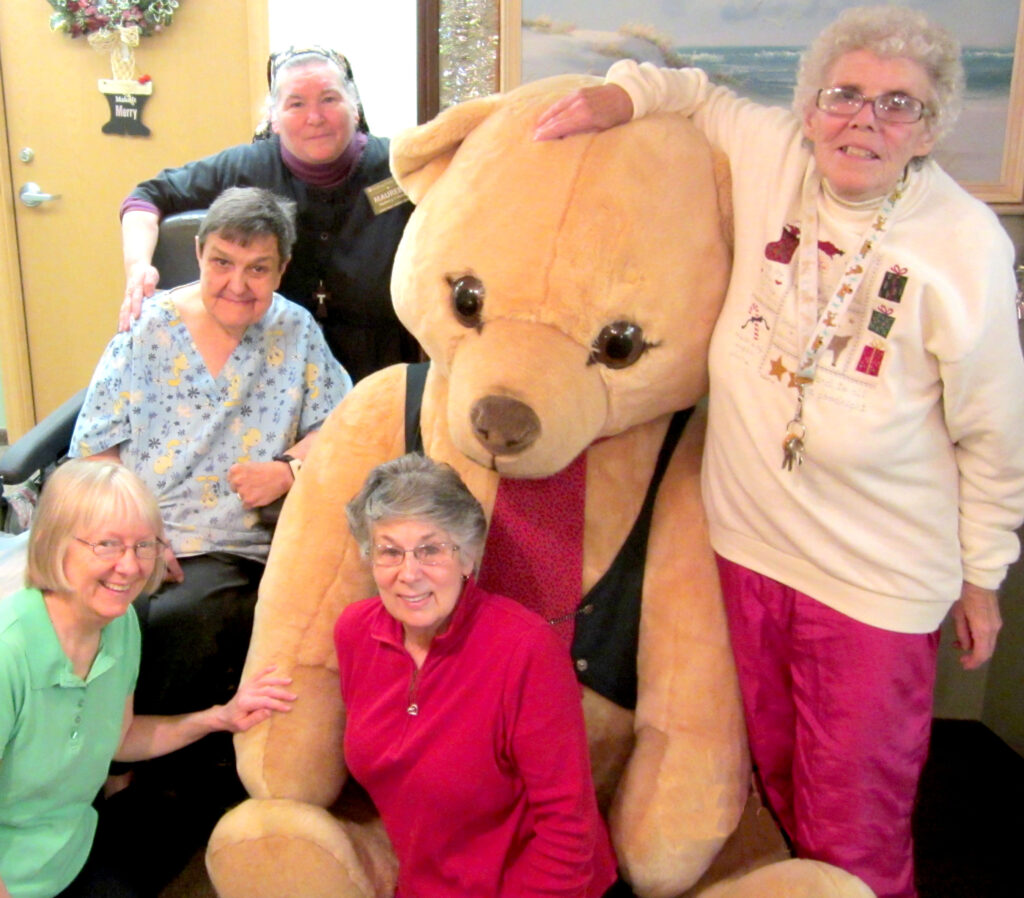 Big Bear is golden in color and stands 7’ tall and about 6’ tall seated in his wicker chair. He is an authentic Steiff Bear.