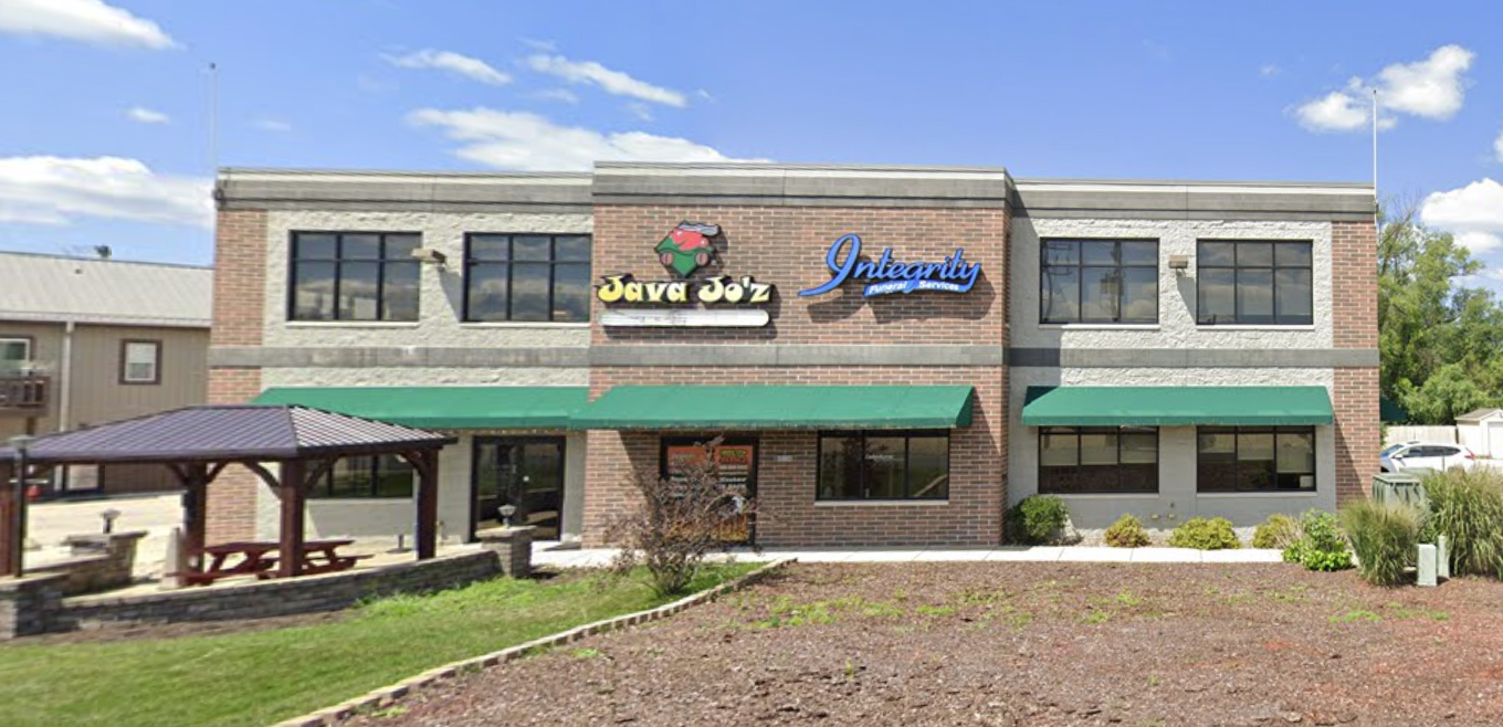 waterford office A brown two-story building with green awnings stands independently and displays the signs for several businesses housed within.