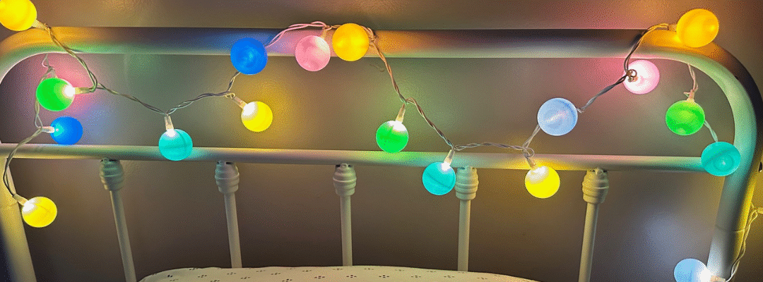 A metal headboard decorated with colorful globe string lights.