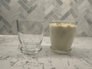 One empty glass and one filled with popcorn and milk
