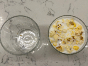 Looking down at an empty glass and a glass filled with popcorn and milk