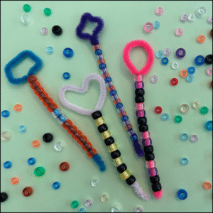Colorful handmade bubble wands with beads on a light green background.