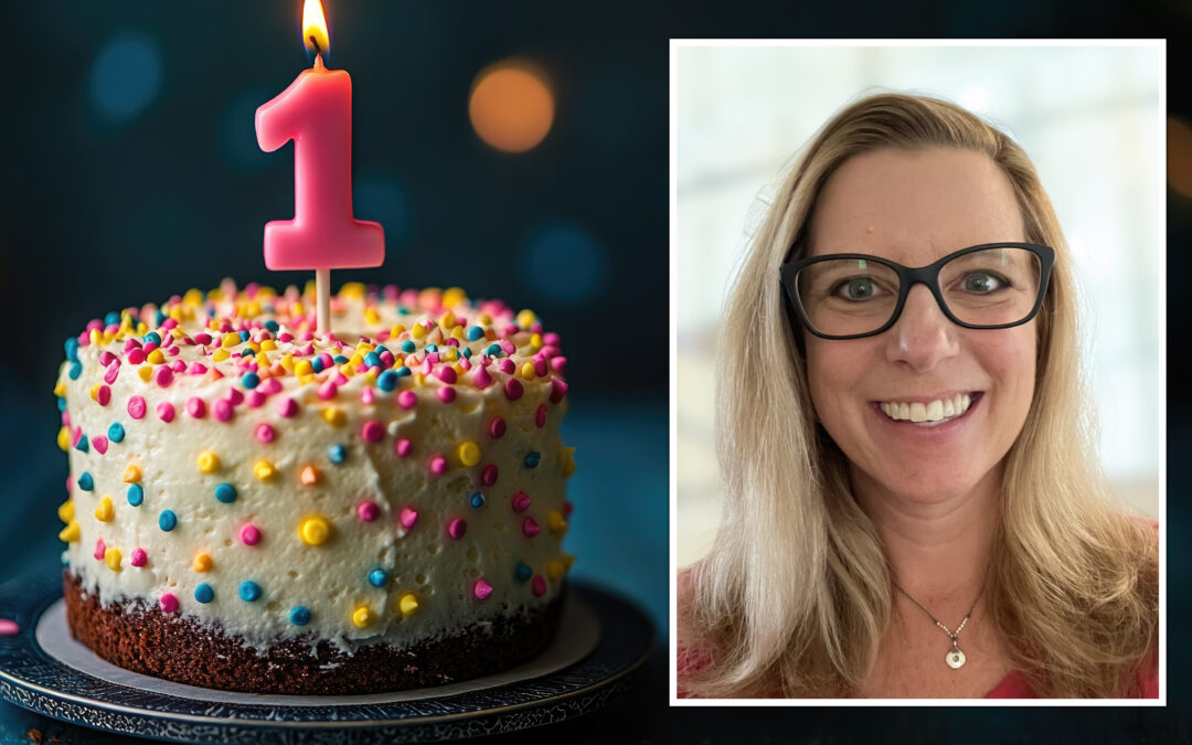 Photo of Kate Davis and a colorfully polka-dotted birthday cake with a 1-year candle burning.