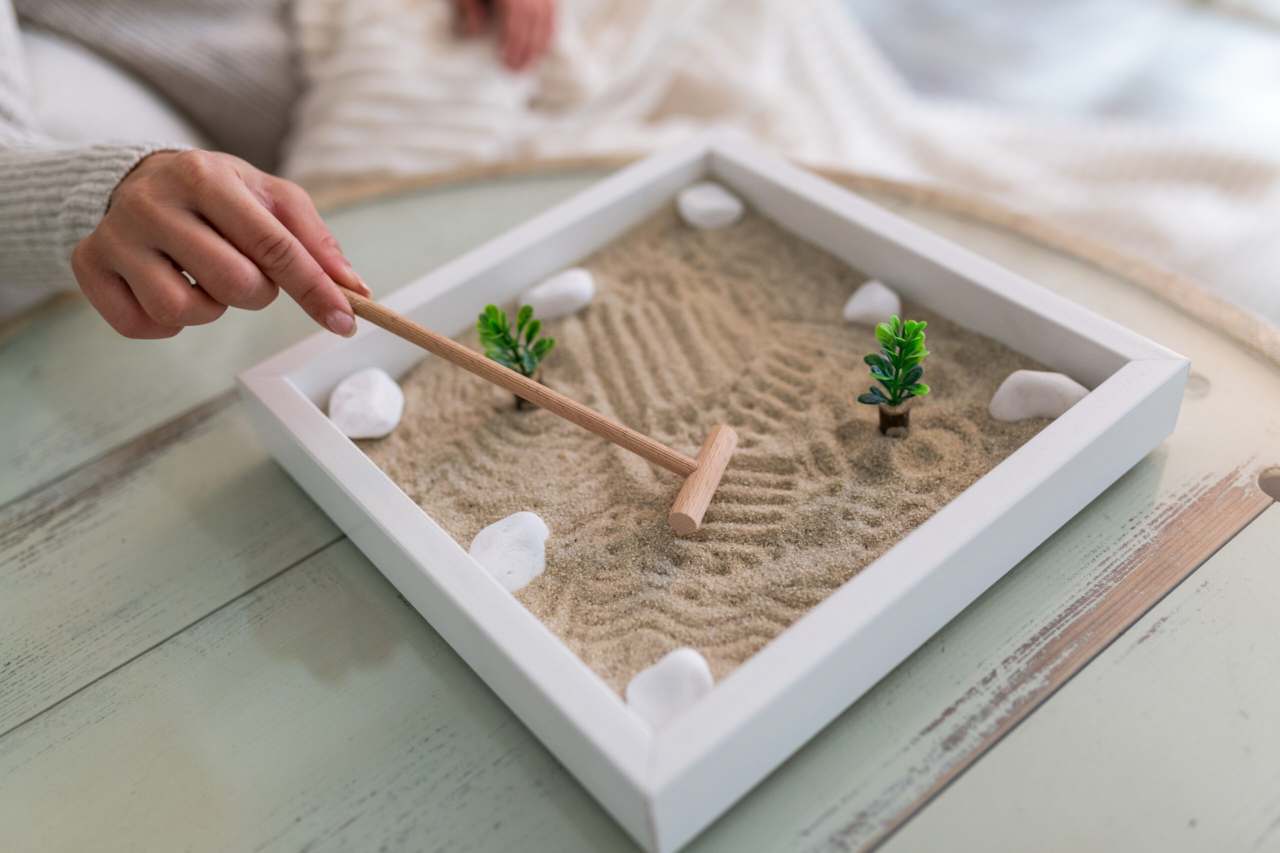 tabletop zen garden with hand holding rake