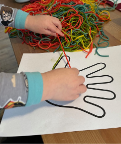 Child tracing handprint outline with colored string